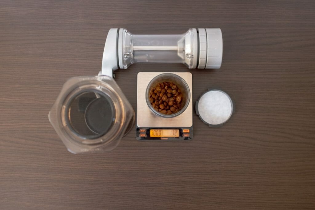 Empty Aeropress set up for inverted method with coffee beans on a scale and a manual coffee grinder on the table.