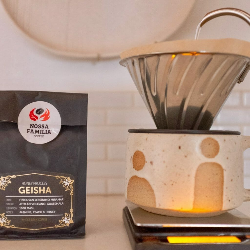 Bag of geisha coffee beans using the honey process with a coffee dripper next to it